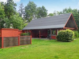 a small red cabin with a fence in a yard at Holiday home Glesborg XL in Glesborg