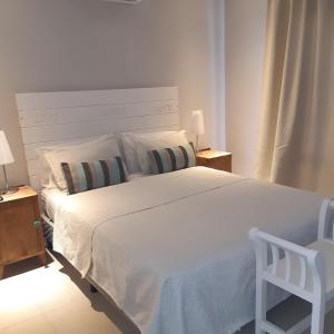 una camera con un grande letto bianco e una sedia di BIG POSADAS a Concepción del Uruguay