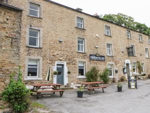 a brick building with picnic tables in front of it at Margaret's Cottage in Feetham