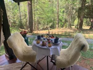 a table with chairs and a table with food on it at Chalé de luxo pertinho de Monte Verde in Monte Verde