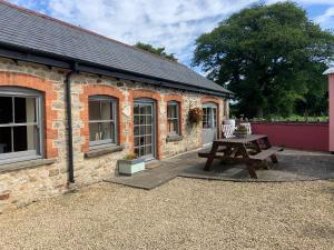 a brick building with a picnic table in front of it at Kingfisher Cottage at Duffryn Mawr Cottages in Hensol