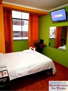 a bedroom with a white bed and a tv at Sombrero de Paja in Chiclayo