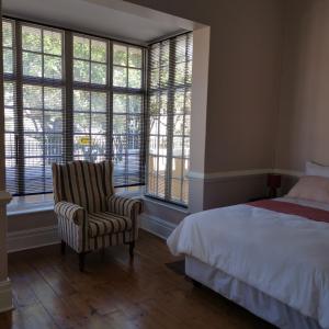 um quarto com uma cama, uma cadeira e janelas em Esperamos em Durban