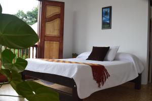 a bedroom with a bed with white sheets and a window at Balcones del Ayer in Salento