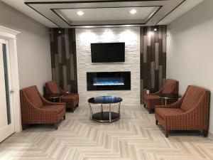 a waiting room with chairs and a fireplace and a tv at Executive Inn and Suites Joaquin in Joaquin