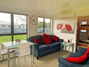 a living room with a blue couch and a table at Mercury Bay Holiday Park in Whitianga