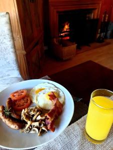 un piatto di prodotti per la colazione con uova e pancetta e un bicchiere di succo d'arancia di Waterford Manor a Henburg Park