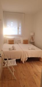 a white bedroom with two beds and a window at Apartamento Bea Beach in Badalona