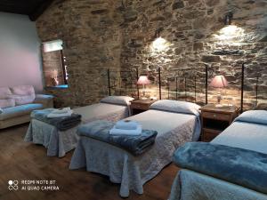 a room with three beds and a stone wall at Albergue Atrio in Tríacastela