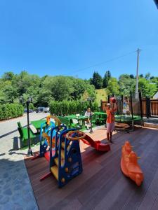 un parque infantil con equipo de juegos y una chica jugando en él en Dream House Hotel & Spa en Kolašin