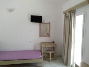 a bedroom with a bed and a tv on the wall at Gorgona apartments & studios in Ipsos