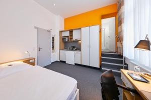 een kamer met een bed, een bureau en een keuken bij Townhouse Düsseldorf in Düsseldorf