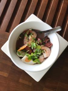 The Riverside Guest House في لامبانغ: وعاء من الحساء مع الربيان والخضار على طاولة