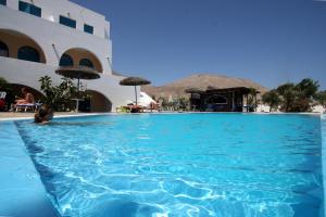 a large swimming pool in a resort with a band at Petra Nera in Perissa