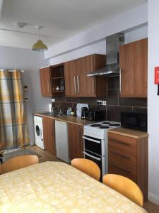a kitchen with wooden cabinets and a table with chairs at Causeway Street Holiday House Self Catering-Portrush in Portrush