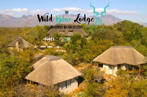 Ce complexe propose des cabanes au toit de chaume et un panneau indiquant le lodge bleu sauvage. dans l'établissement The Wild Blue Lodge SAFARI & SPA, à Hoedspruit
