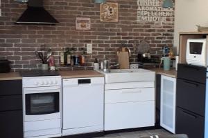 a kitchen with white appliances and a brick wall at TY FAROMA - SUPERBE MAISON DE VACANCES in Sarzeau +3 photos