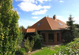 a house with a brown roof and some bushes at Ferienhaus Zur Schmiede in Göhren-Lebbin