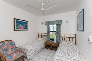 two beds in a room with a chair and a window at Santorini - Akrotiri 3 in Ballito