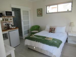 a bedroom with a bed and a desk and a window at Royal@Sea2 in Muizenberg