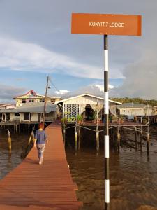 a man walking on a dock in the water at Kunyit 7 Lodge in Bandar Seri Begawan