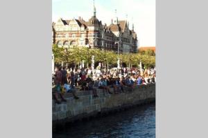 a crowd of people sitting on a wall next to a river at Guest rooms harbor view in Copenhagen