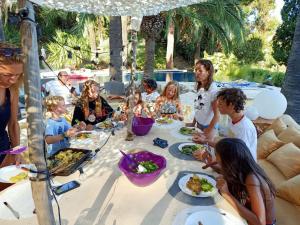 Un groupe de personnes assises autour d'une table et mangeant de la nourriture dans l'établissement Villa La Renarde, au Lavandou