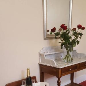 a vase of roses on a table with a bottle of champagne at Hotel Raymond VII in Cordes-sur-Ciel