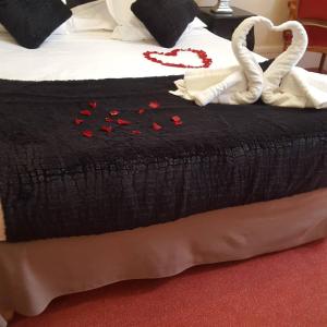 a bed with a black blanket with red roses on it at Hotel Raymond VII in Cordes-sur-Ciel