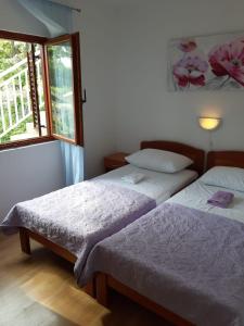 two beds in a room with a window at Apartmani Pipin - Prigradica, kod Caffe Tempera in Prigradica