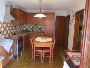 una cocina con armarios de madera y una mesa con sillas. en Ciesa Dei Maestri en Sottoguda