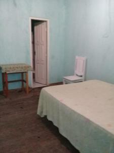 a bedroom with a bed and a table and a door at Suites para São João em Amargosa in Amargosa