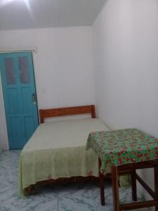 a bed and a stool in a room with a blue door at Suites para São João em Amargosa in Amargosa