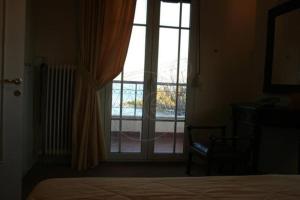 um quarto com uma cama e uma grande janela em Corfu Aegli appartments em (( Filaréton ))