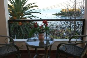 uma mesa com um vaso de flores numa varanda em Corfu Aegli appartments em (( Filaréton ))
