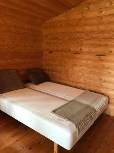 a bed in a room with wooden walls at Koskenselkä Camping in Puumala