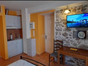 a kitchen with a table and a tv on a wall at VERANDA BLUE - POROS in Poros