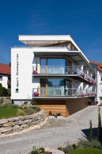 a large white house with a balcony on a hill at Apart Rosengarten in Immenstaad am Bodensee