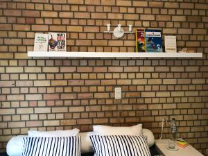 Habitación con pared de ladrillo, cama y almohadas en Lumineux appartement, en Louvain-la-Neuve