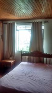 1 dormitorio con 1 cama grande y ventana en Pousada Santa Felicidade Trieste D en Curitiba