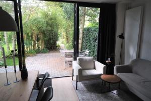 a living room with a white couch and a glass door at B&B behind the tree in Hoofddorp