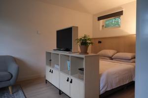 a bedroom with a bed with a television and a chair at B&B behind the tree in Hoofddorp