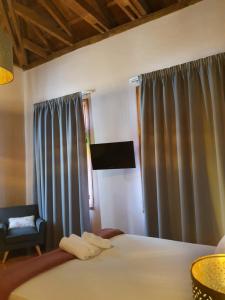 a bedroom with a bed with curtains and a chair at Porta Medina Boutique Hotel in Heraklio Town
