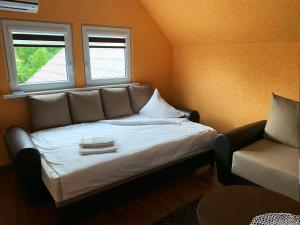 a bed in a room with a couch and a chair at Prie Ąžuolo in Zarasai