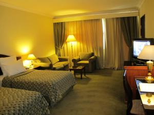 una camera d'albergo con due letti e una televisione di Grand Pyramids Hotel a Il Cairo