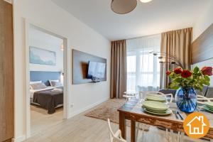 ein Wohnzimmer mit einem Tisch und ein Zimmer mit einem Bett in der Unterkunft Apartamenty Aquamarina Onyx - visitopl in Misdroy