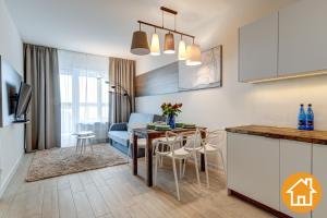 eine Küche und ein Wohnzimmer mit einem Tisch und einem Sofa in der Unterkunft Apartamenty Aquamarina Onyx - visitopl in Misdroy