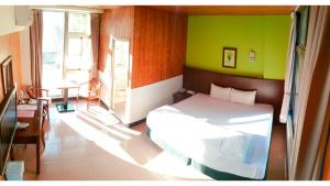 a bedroom with a white bed and a green wall at Royal Holiday Imv in Baihe