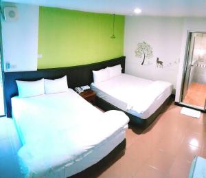 two beds in a room with a green wall at Royal Holiday Imv in Baihe