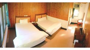 two beds in a room with wood paneling at Royal Holiday Imv in Baihe